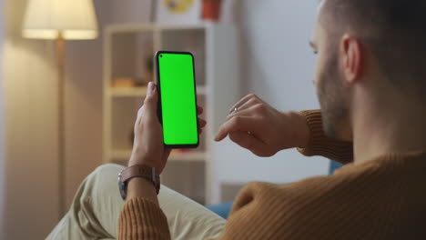man-is-shopping-online-ordering-in-app-in-smartphone-swiping-and-tapping-by-finger-green-screen-on-gadget-modern-technology-and-service